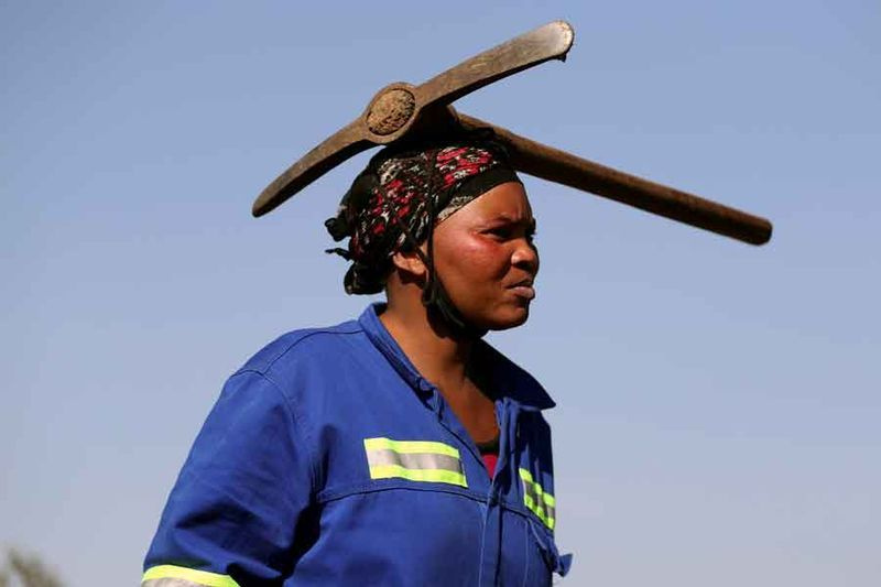 Prichádza žena s krompáčom na hlave, keď sa hľadači šťastia hrnú do dediny KwaHlathi pri hľadaní toho, čo považujú za diamanty, mimo Ladysmith, provincia KwaZulu-Natal, Južná Afrika 14. júna 2021. — Reuters/Siphiwe Sibeko