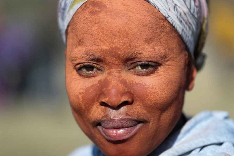 Žena, ktorá si na tvár nanáša hlinu, aby si chránila pokožku pred slnkom, vyzerá, ako sa do dediny hrnú hľadači šťastia po tom, čo boli na sociálnych sieťach zdieľané obrázky a videá, na ktorých ľudia oslavujú po tom, čo našli to, čo považujú za diamanty v dedine KwaHlathi mimo Ladysmith, v provincii KwaZulu-Natal, Južná Afrika, 14. júna 2021. — Reuters/Siphiwe Sibeko